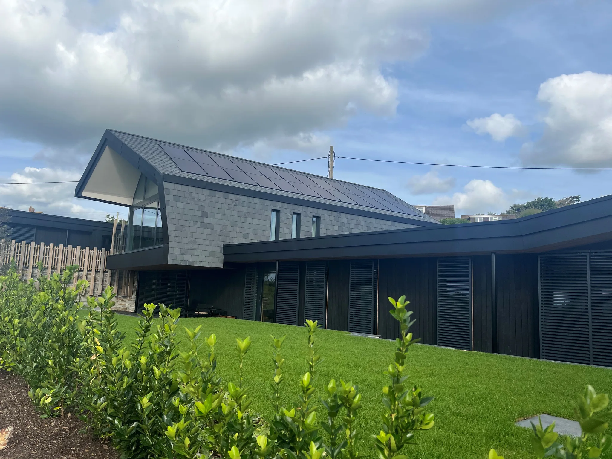 Contemporary house with slate roof and solar panels under cloudy sky